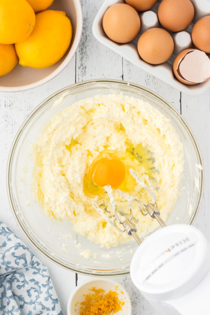 Large eggs mixed into lemon pound cake wet ingredients with an electric mixer.