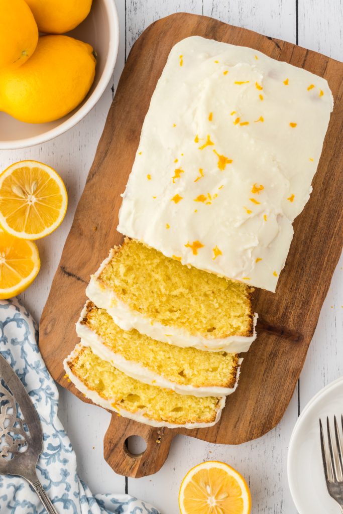 Sliced Meyer Lemon pound cake with a citrus glaze on a wooden cutting board.