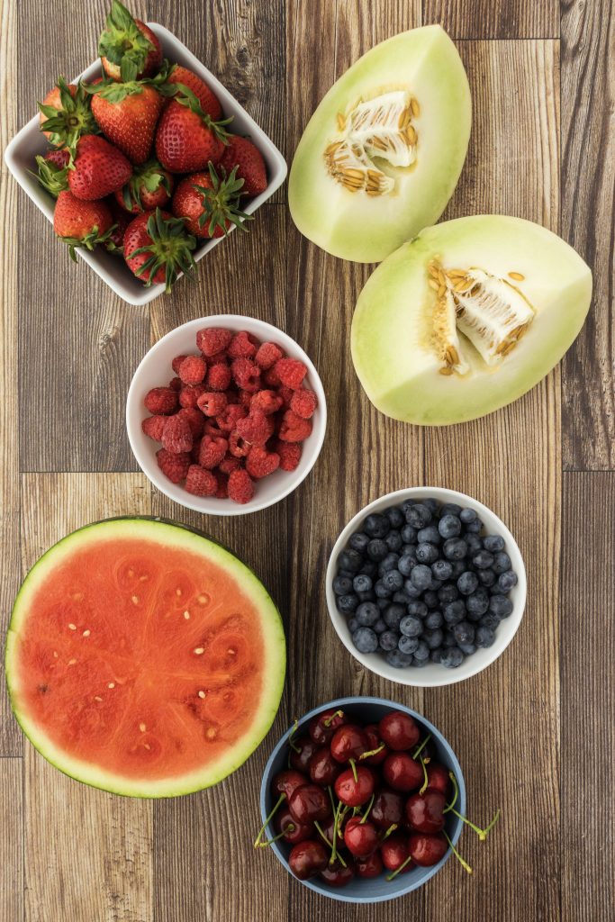 July fruit salad recipe with watermelon, honeydew melon, berries, and cherries.