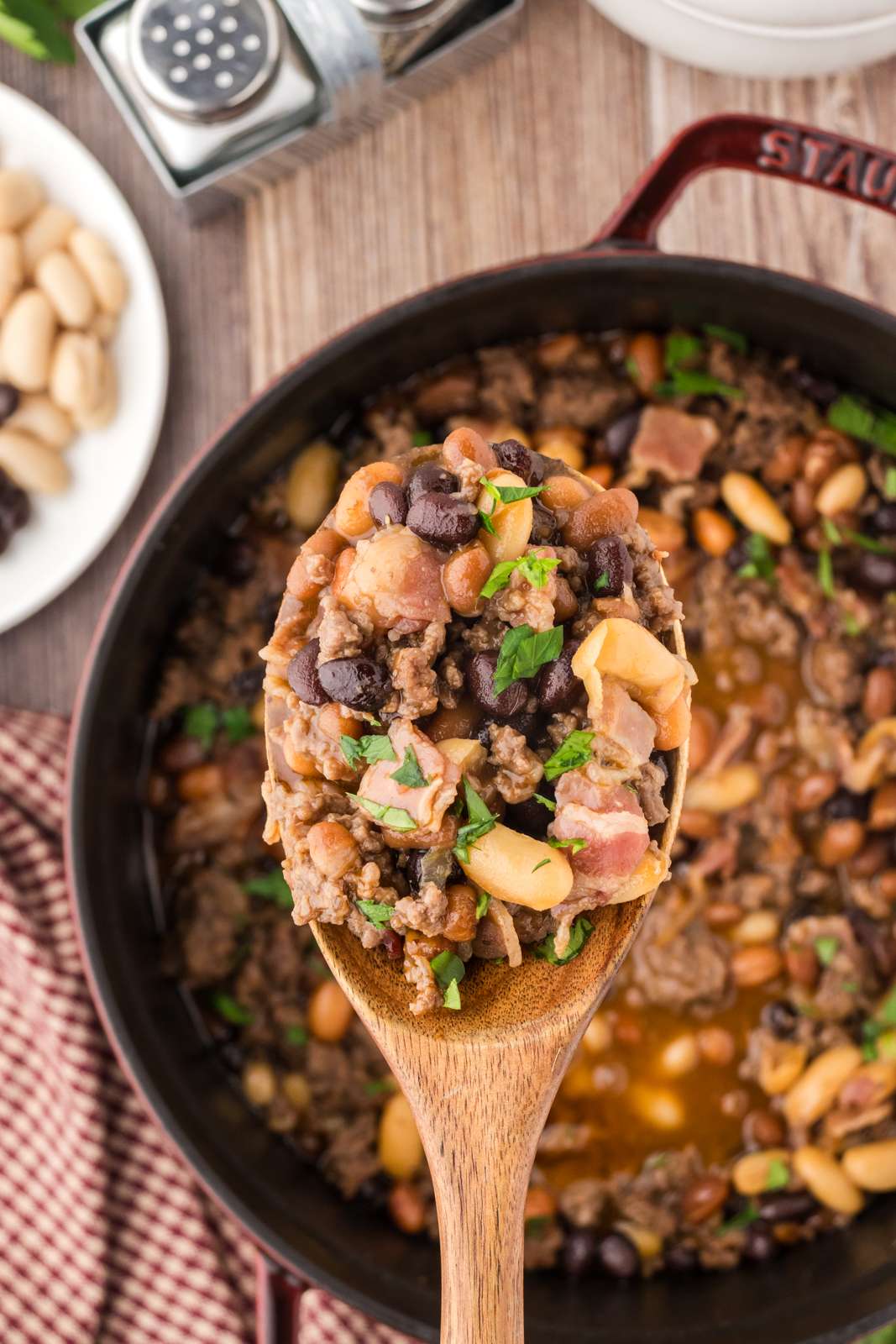 Serving the best baked beans with a wooden spoon as a hearty side dish.