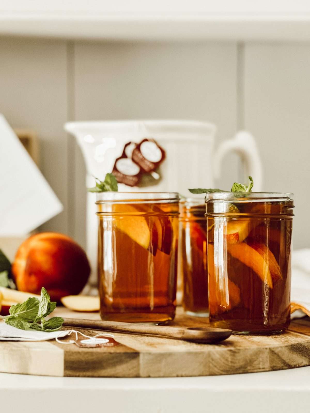 Stoneware tavern pitcher with glasses of sweet peach tea for summer entertaining.