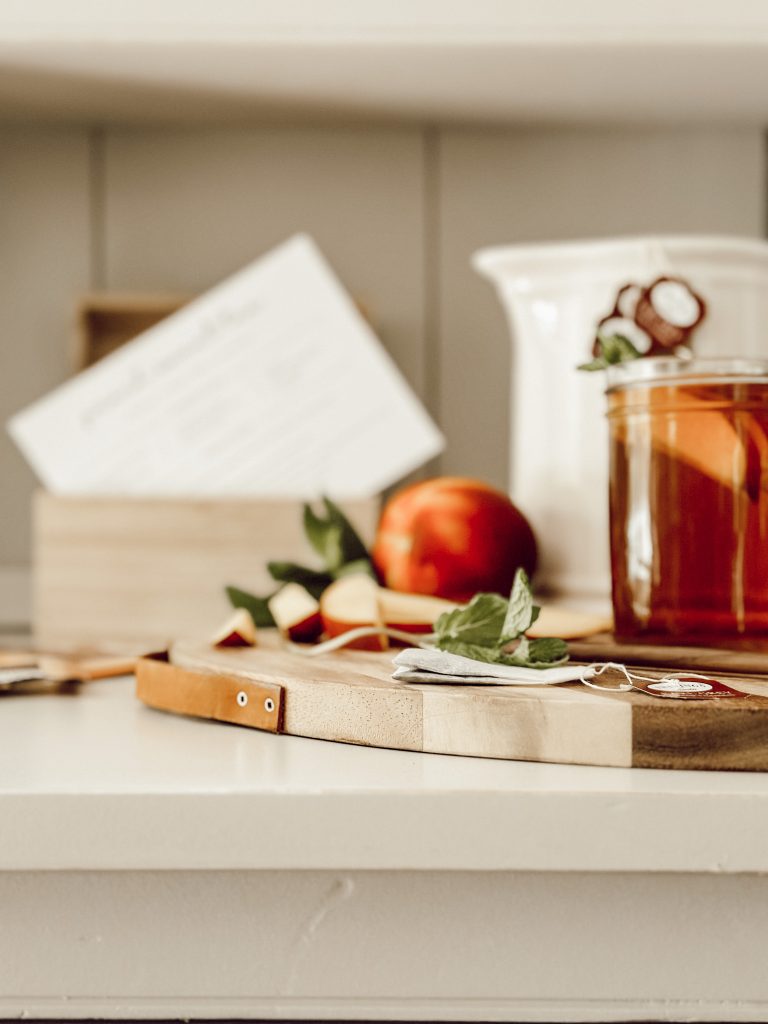 Sweet peach iced tea in a ceramic pitcher poured into mason jars for a cool summer drink.