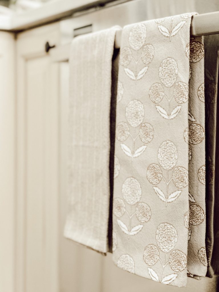 Block print dish towel hanging on the dishwasher with a striped towel.