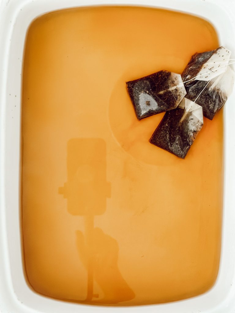 Tea bags steeping in water for tea staining flags for vintage decor.