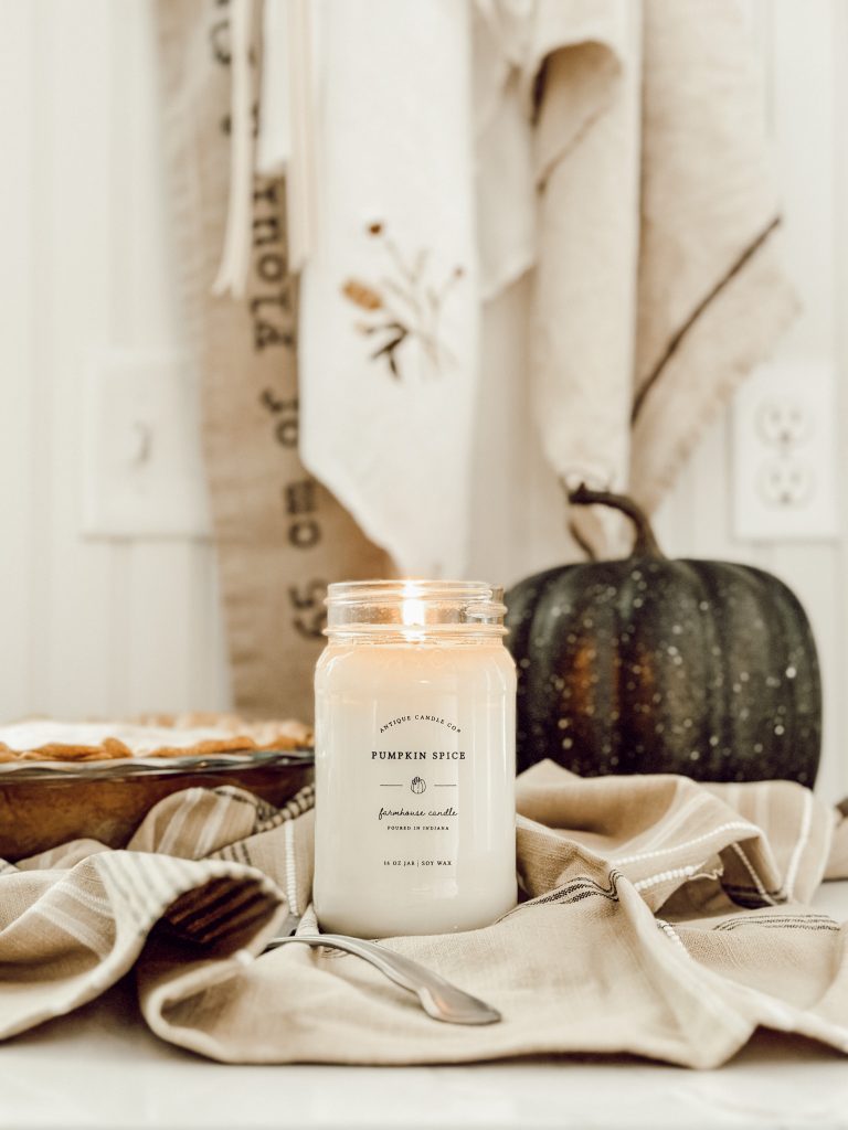 Fall pumpkin scented candle in farmhouse kitchen with green pumpkin.