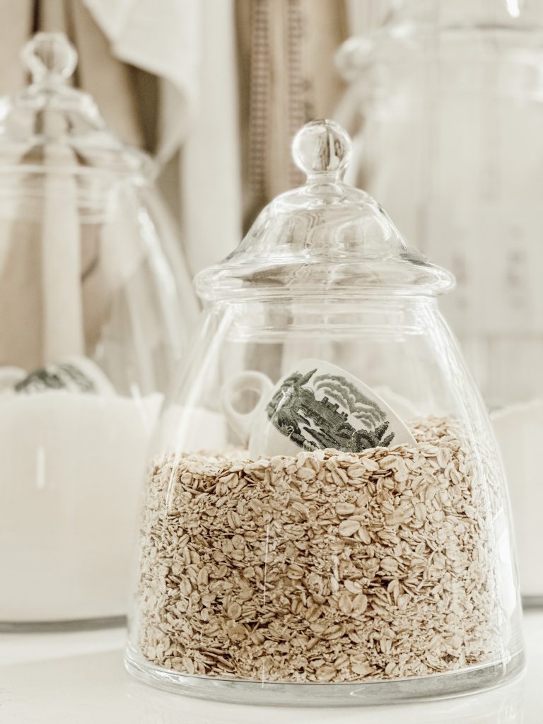 Glass jars with ironstone scoops on kitchen countertops for baking and cooking.