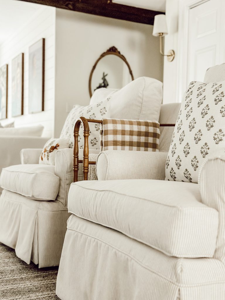 Arm chairs in sitting room with throw pillows, gingham throw blanket, and a wool plaid rug.