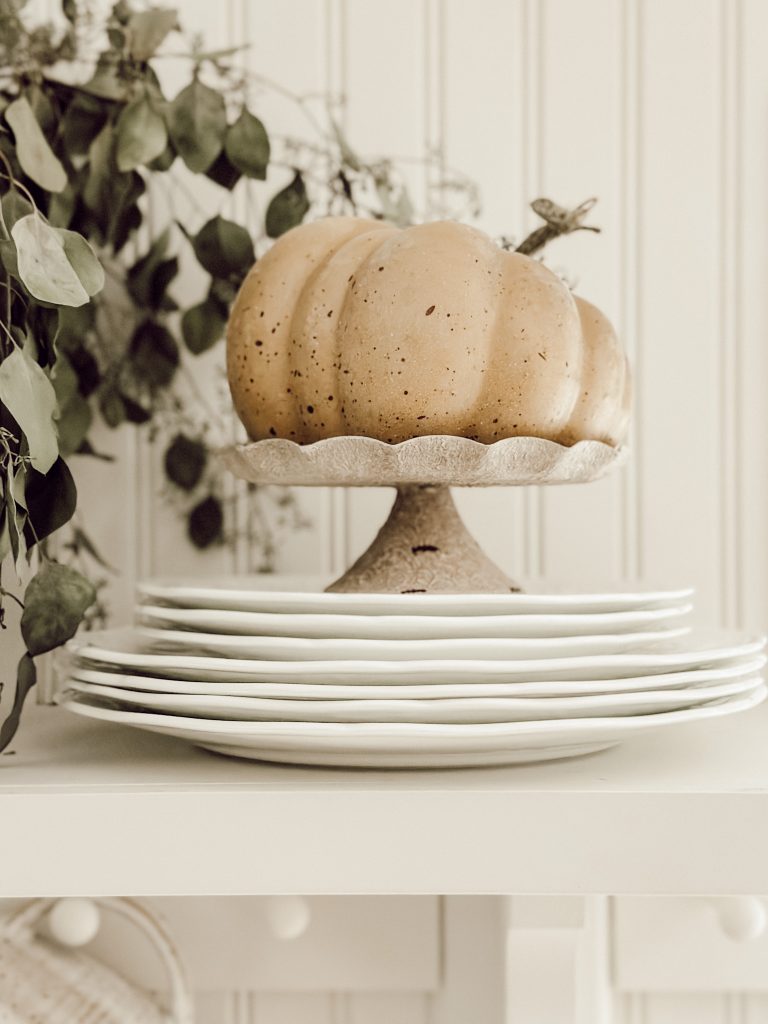 Small pumpkin on white ironstone plates for simple fall decorations.