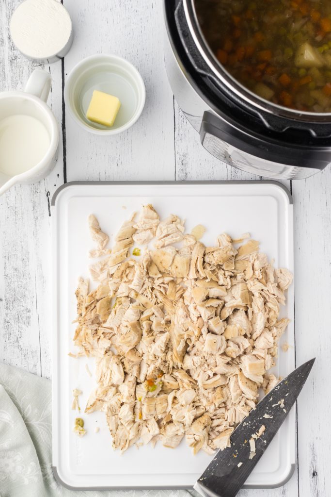 Diced chicken breasts on cutting board cooked in electric pressure cooker.