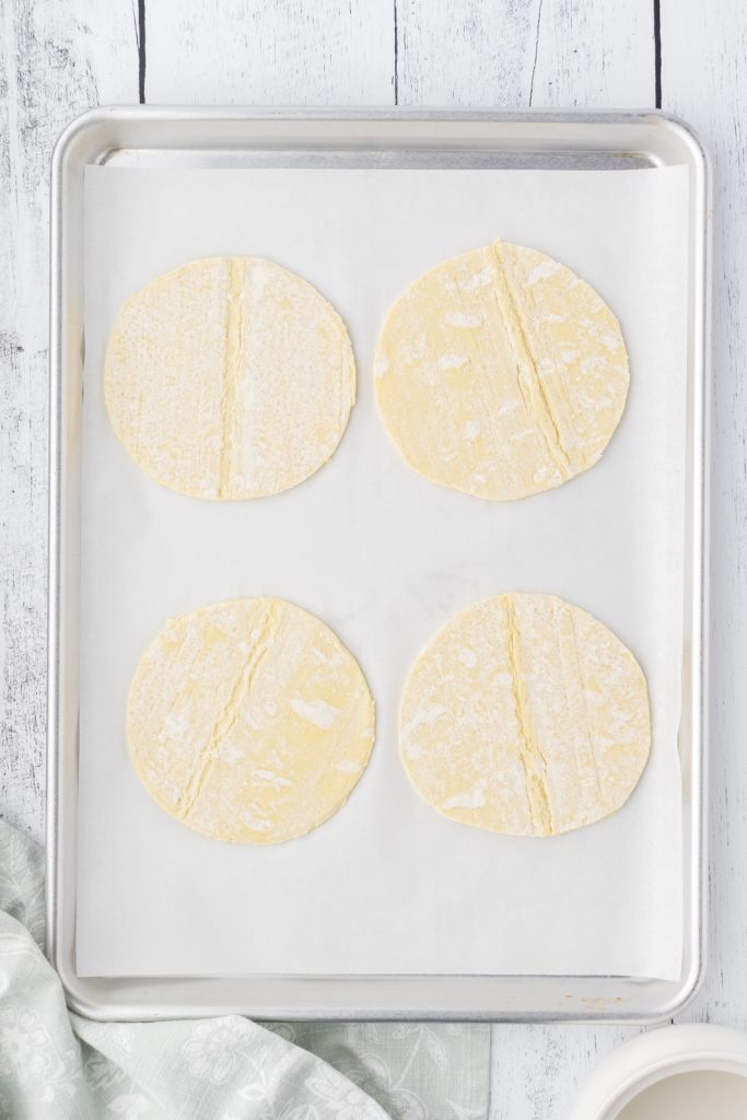 Puff pastry circles on a parchment lined cookie sheet.