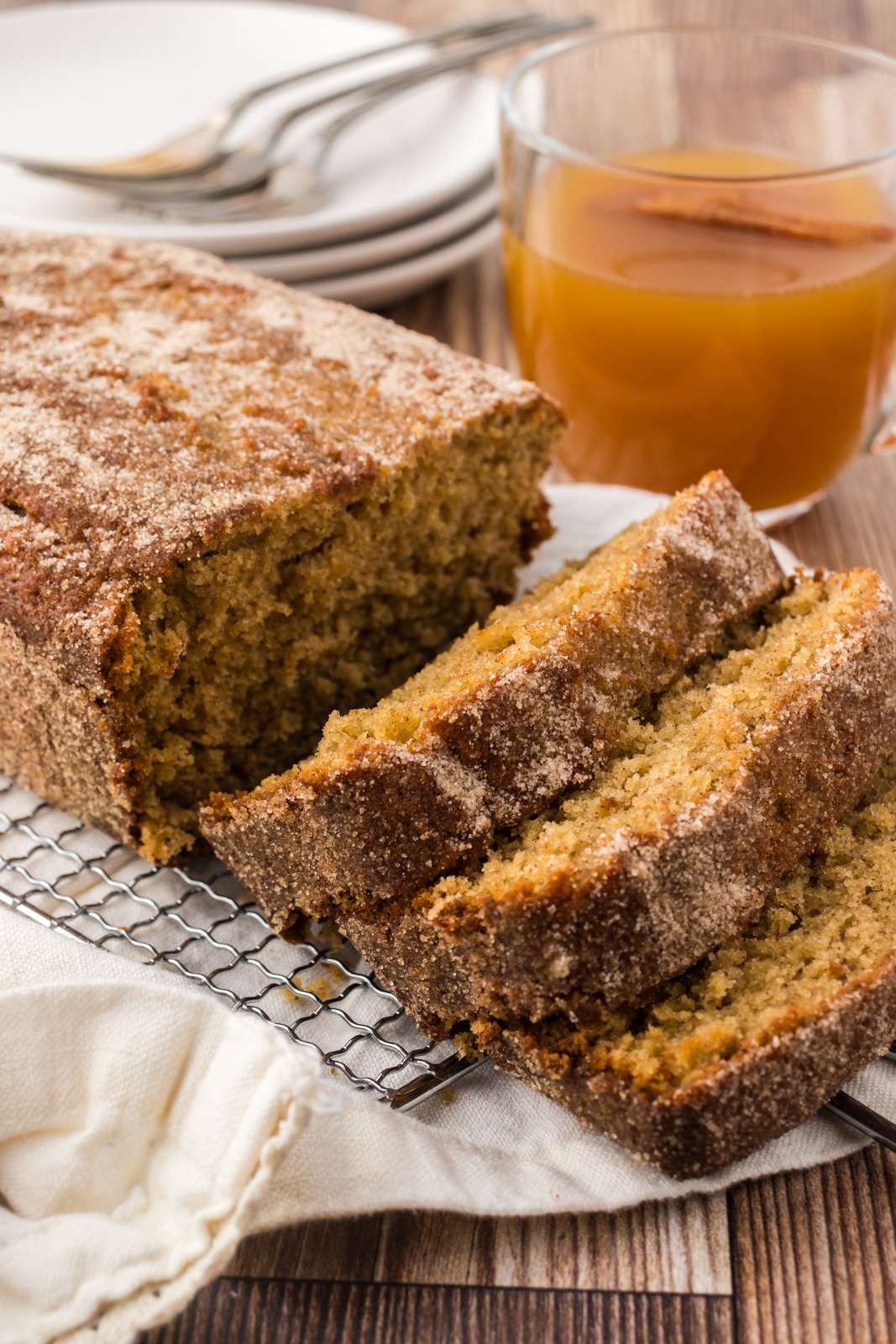 Sliced apple cider loaf with a glass of hot apple cider for the fall season.