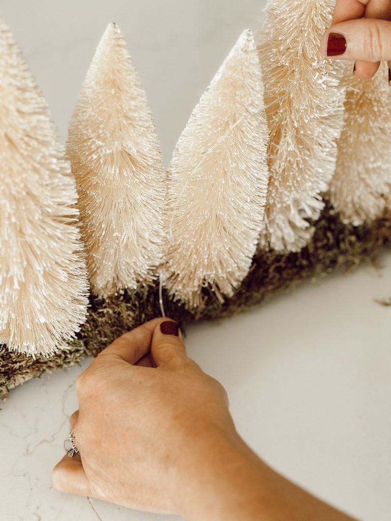 Stringing fairy lights through the Christmas decoration for the holiday season.