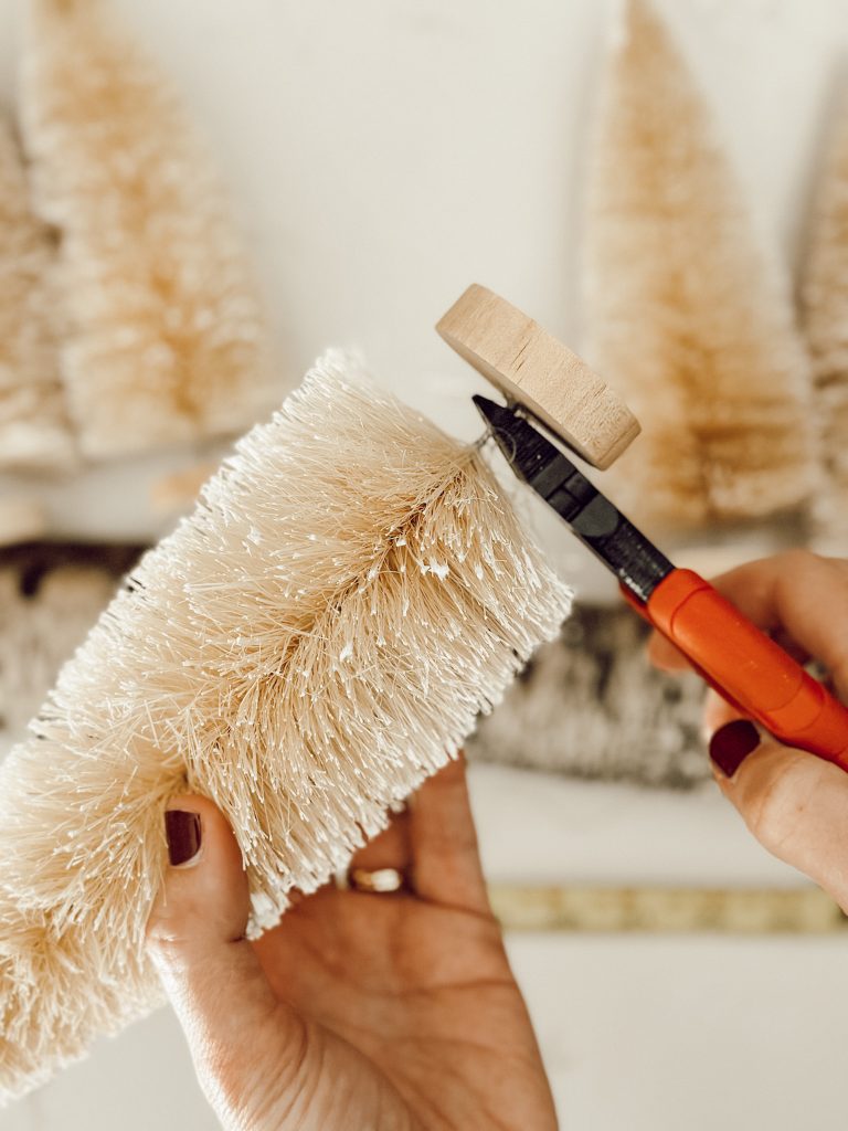 Use wire cutters to remove the wooden base of the bottle brush trees to hot glue them to the centerpiece base.