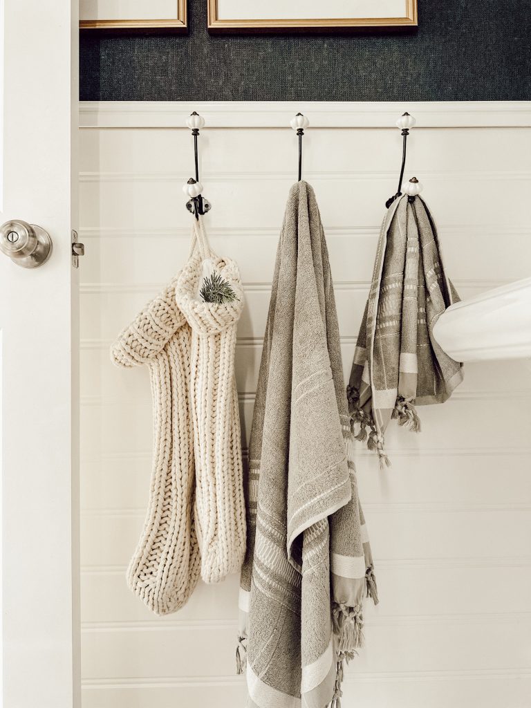 Green Bath towels hanging on hooks in bathroom to add a little holiday cheer.