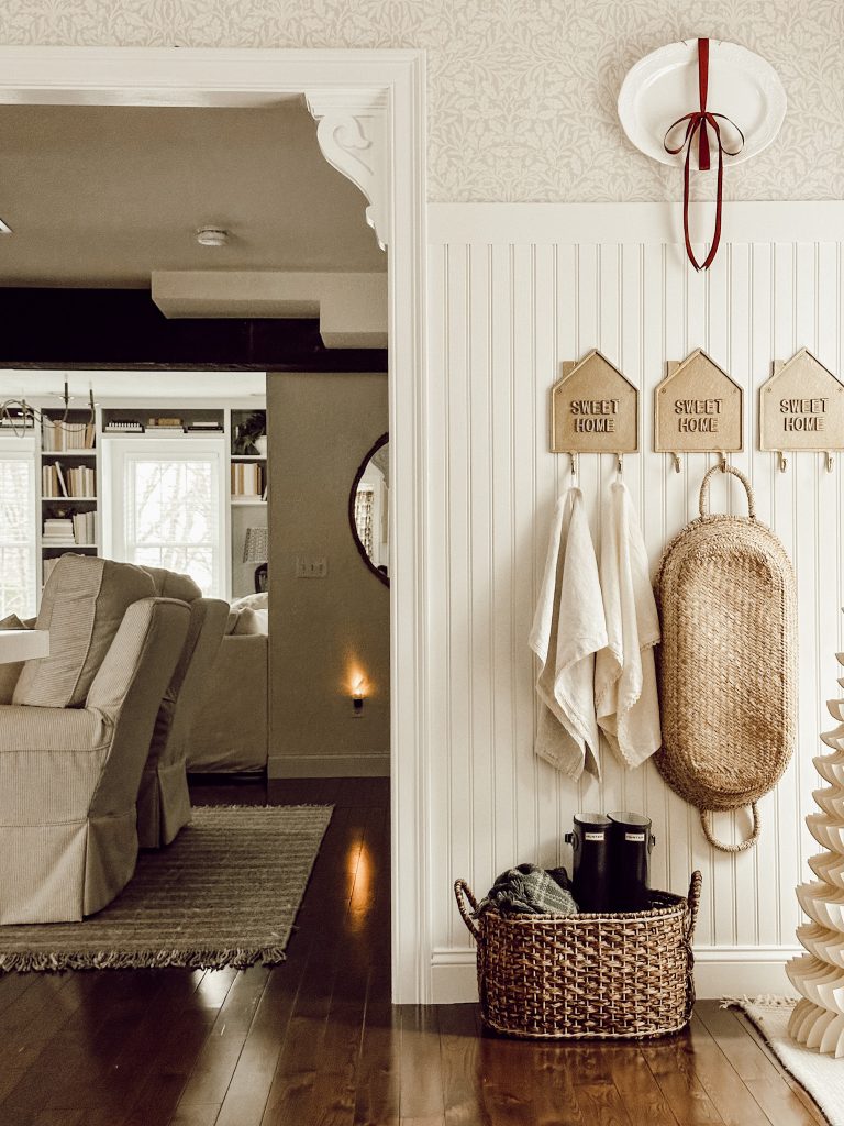 A holiday themed entryway with a neutral color scheme and a pop of burgundy.