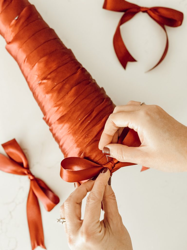 Begin pinning the Christmas bows to the cone tree with straight pins.