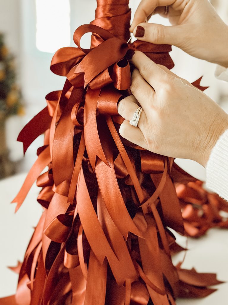 Heidi using a pin to attach the bows to the cone tree.
