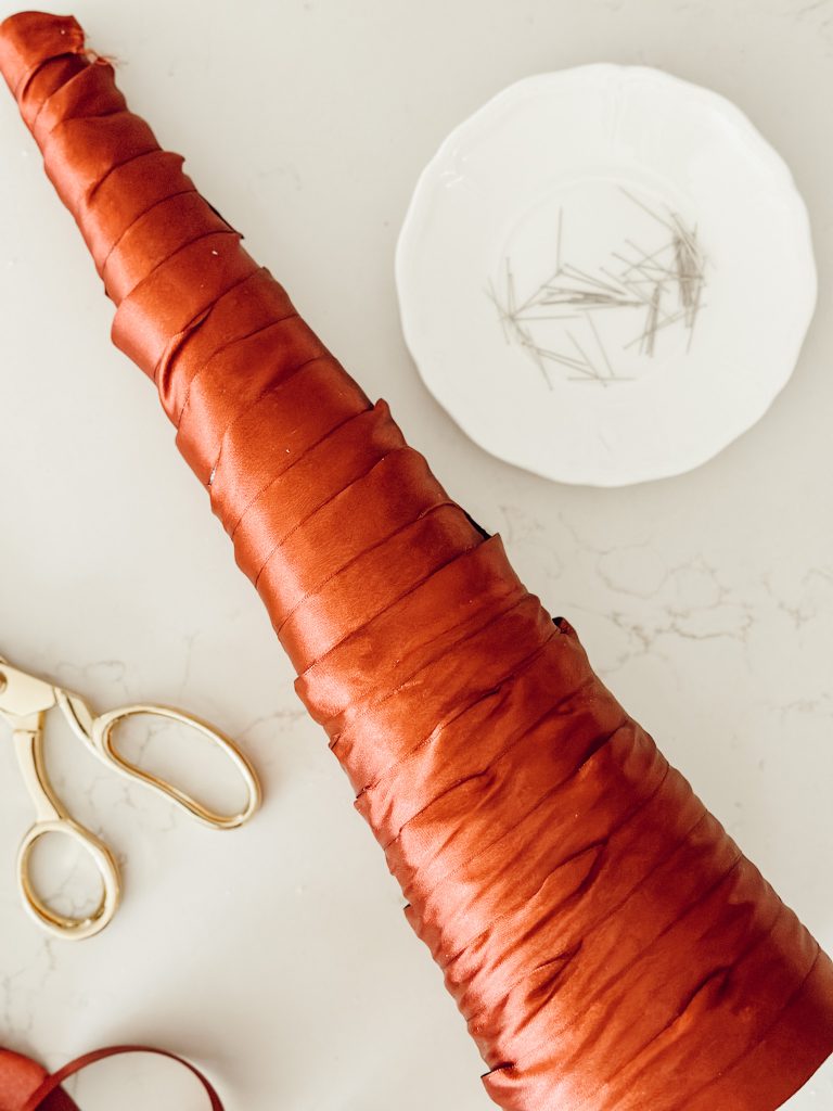 The styrofoam cone covered in satin ribbon for the Christmas craft project.