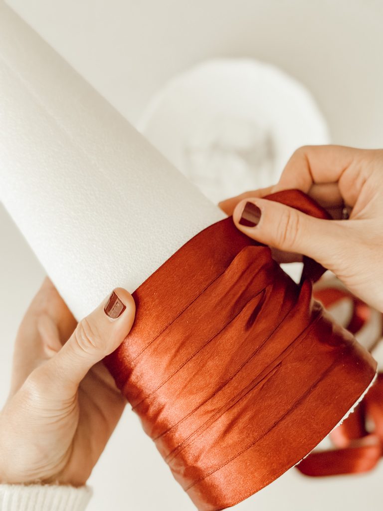 Wrap the styrofoam cone with satin Christmas ribbon to make the holiday DIY project.