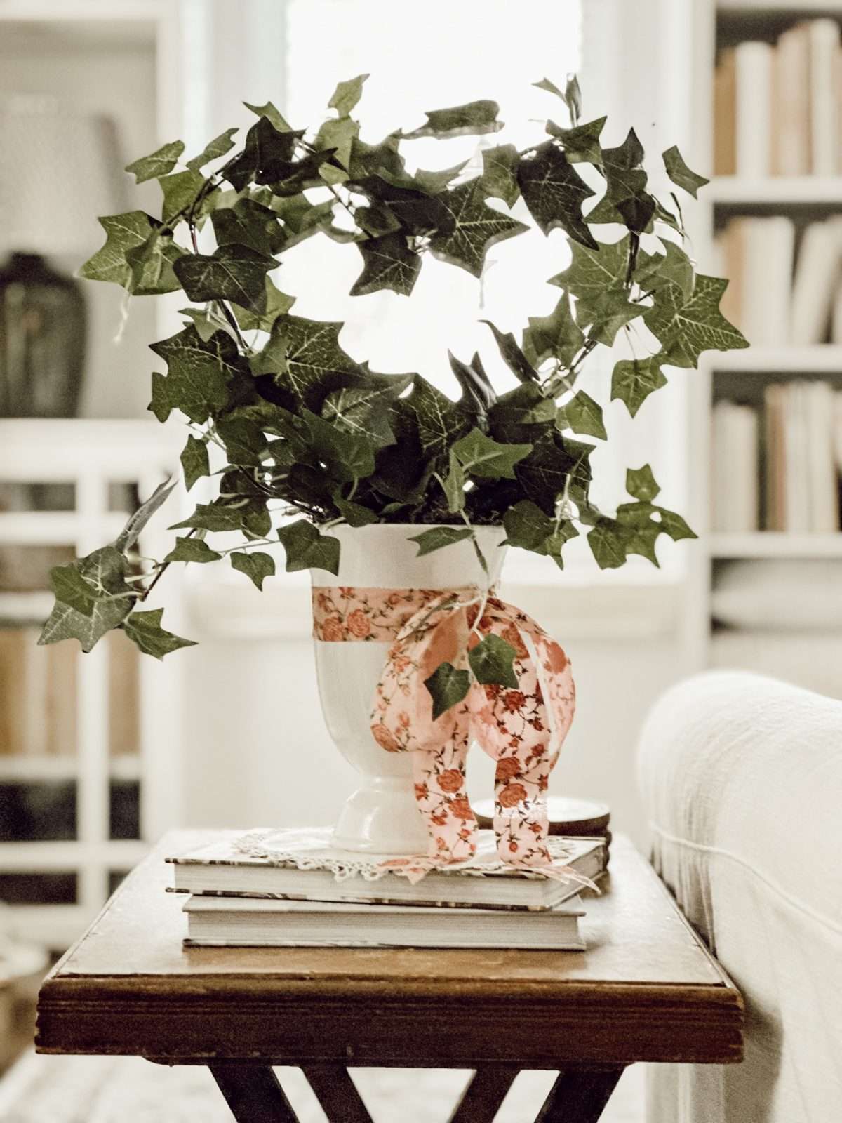 Heart topiary made with faux ivy, clothes hanger, green moss, and ribbon displayed in living room.