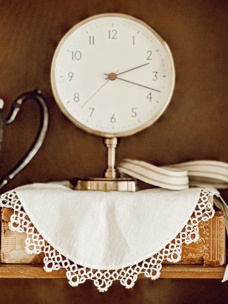 Secretary desk decorating ideas with a clock, hardcover books, and heirloom pieces.
