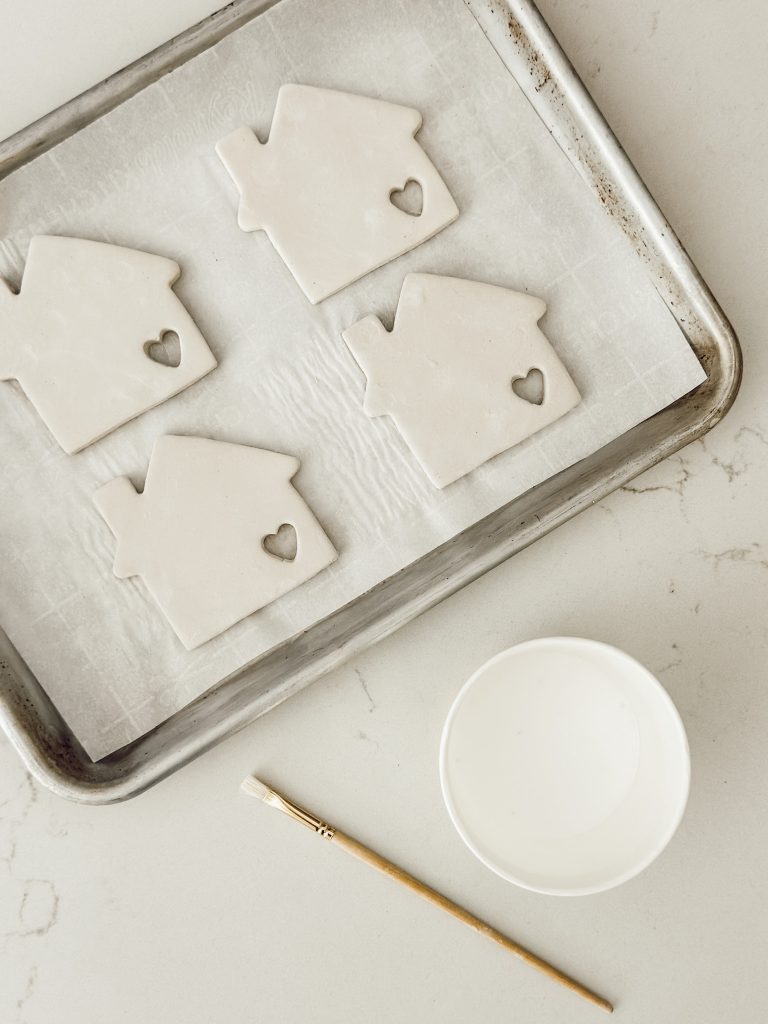 Dried clay coasters with a bowl of Mod Podge and a paintbrush to apply it.