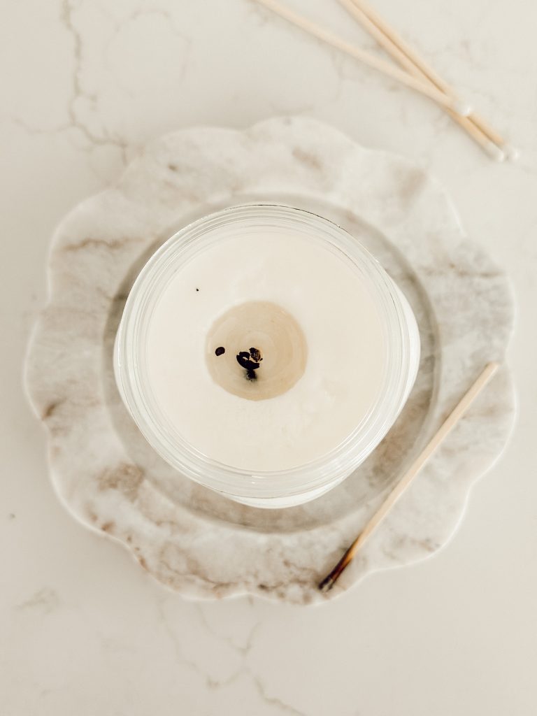 A burned candle on a marble scalloped edge candle tray with wooden matches.