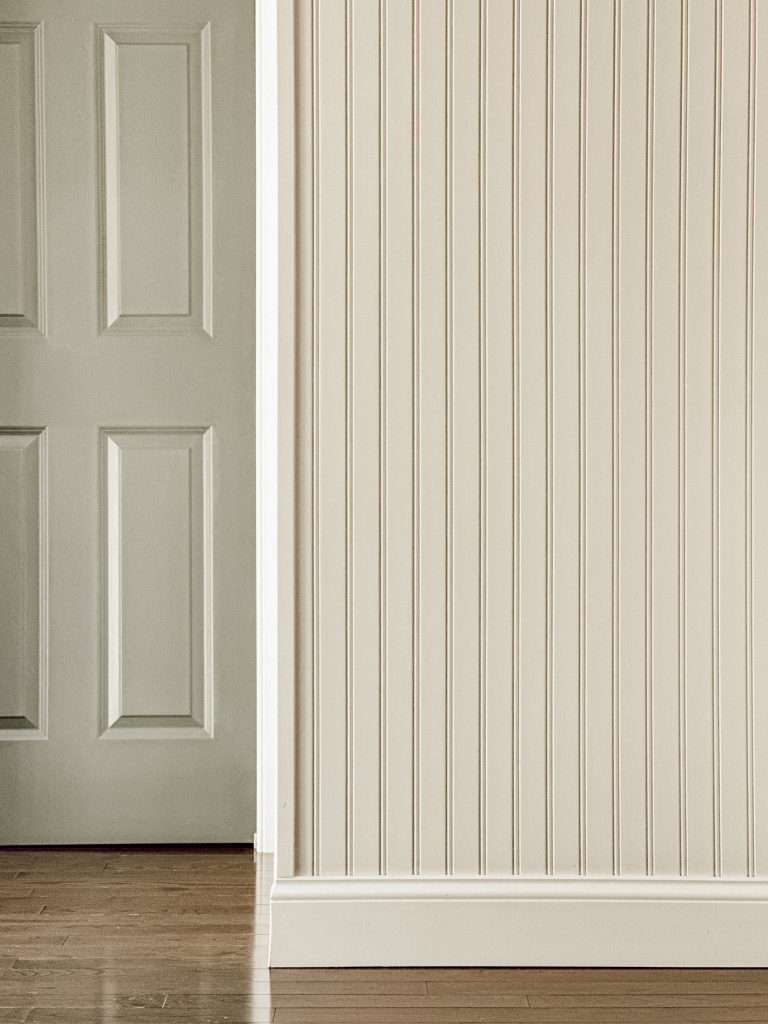 Beadboard accent wall in the kitchen with a green pocket door to the pantry.