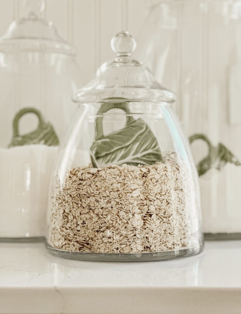 Clear containers on our kitchen countertop filled with flour, sugar, and oats with cabbageware cups for scooping.
