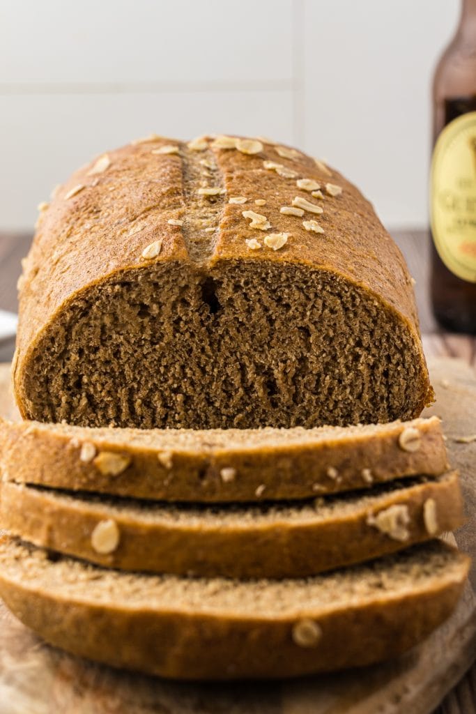 Loaf of Irish black bread sliced with a sharp knife for serving with cup of soup.