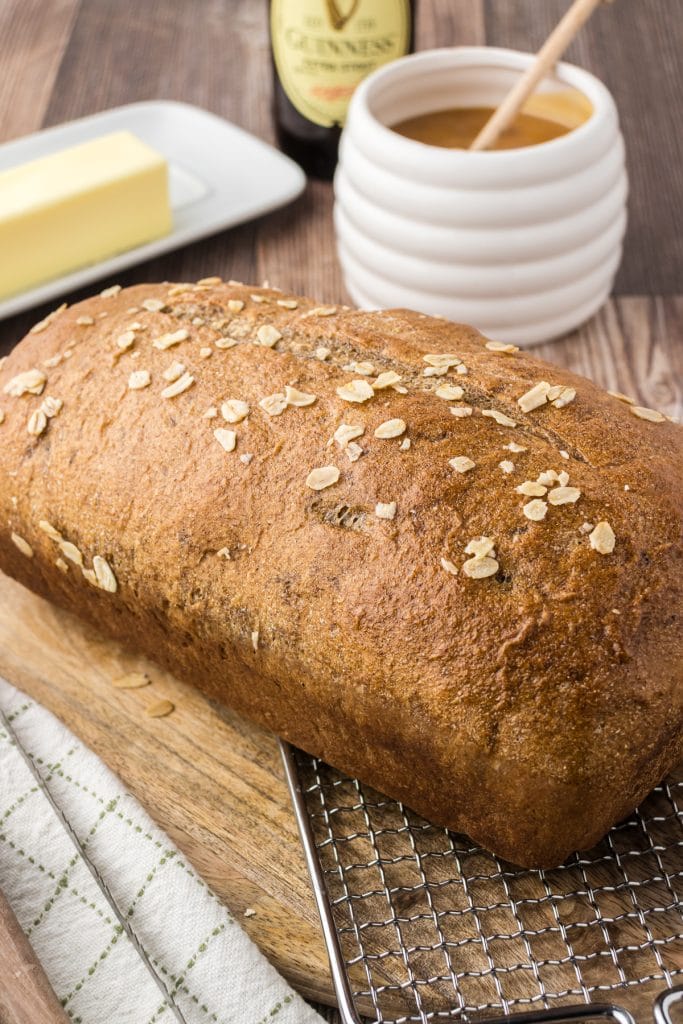 Traditional Irish brown bread on a cutting board with a pot of honey and a stick of butter.