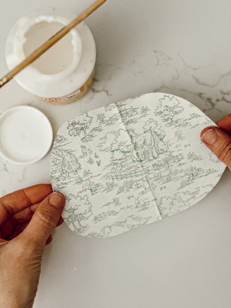 Placing the paper napkin with the cottage scene on top of the shell with the Mod Podge.