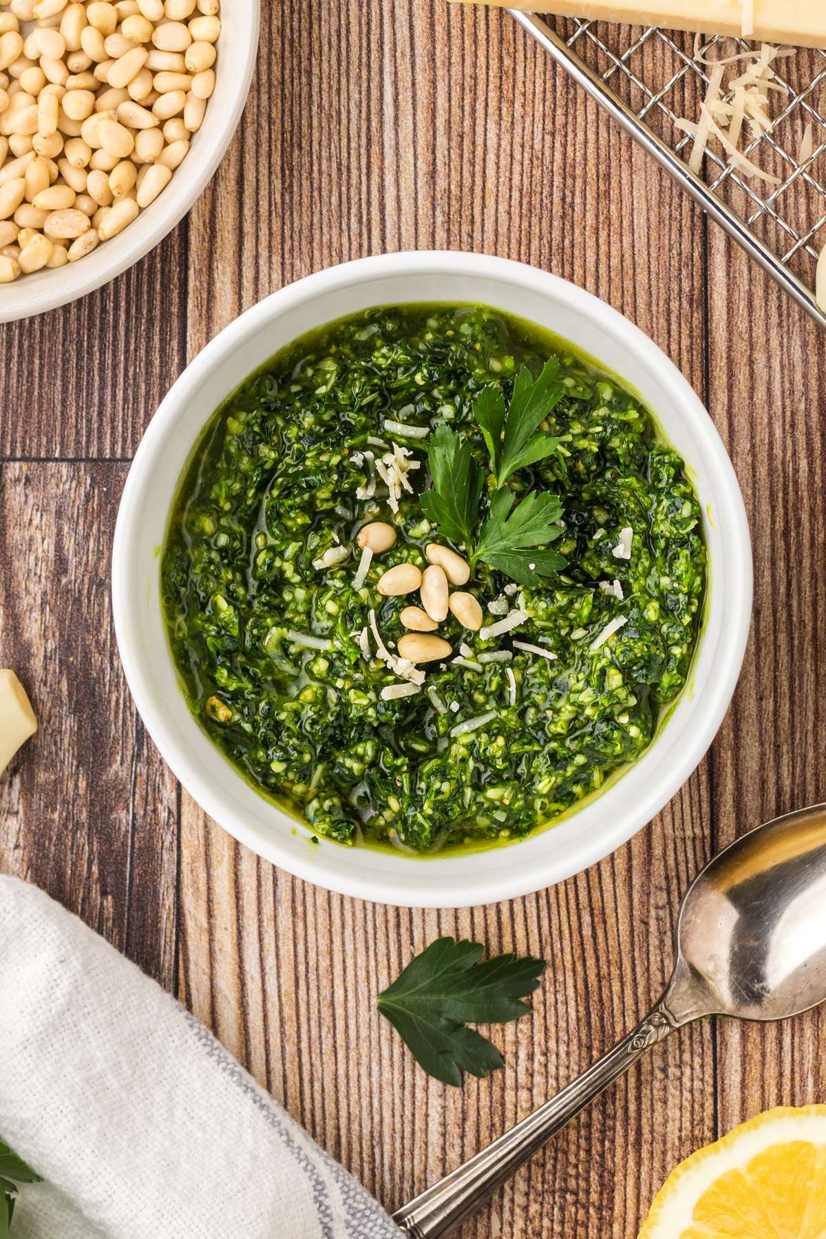 Bowl of parsley pesto topped with toasted pine nuts.