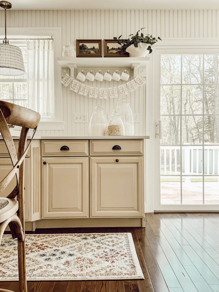 Peter Rabbit garland hanging in cozy cottage kitchen with white coffee mugs.