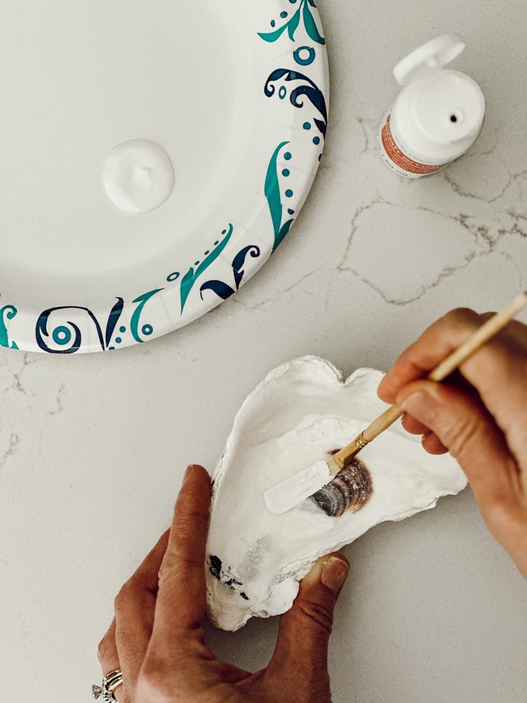 Using white acrylic paint, paint the inside of the oyster shell white with a small paintbrush.