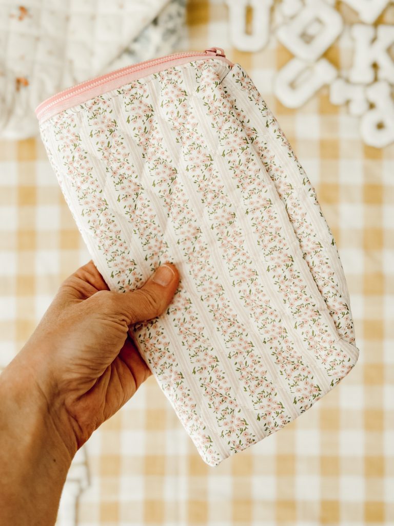 Fold the quilted floral makeup bag in half to find the center of the pouch.