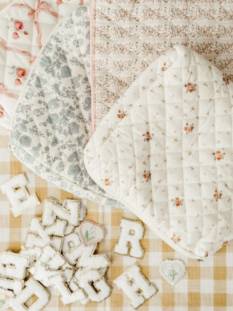 The simple supplies to make DIY makeup bags include floral quilted pouches and iron-on varsity letters.