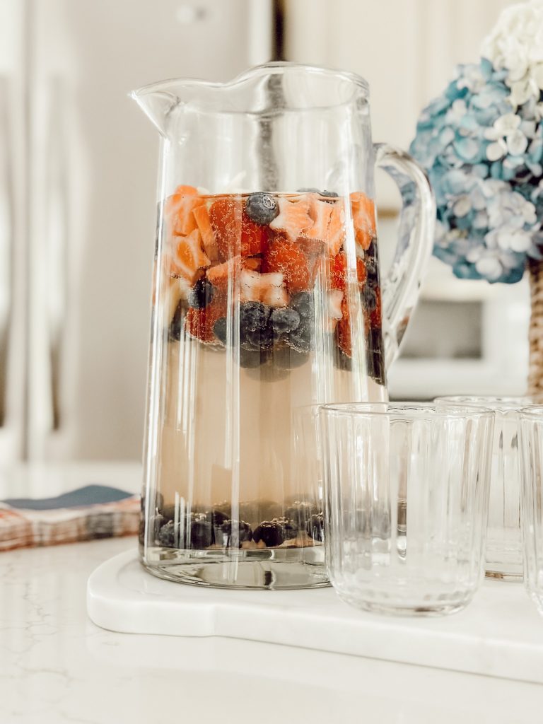 Summer white sangria in a glass pitcher with white wine, vodka, fresh strawberries, and fresh berries.