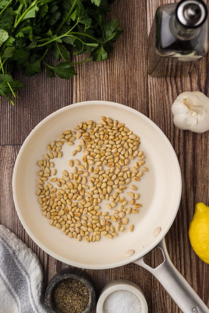 Toasted pine nuts in a saucepan for a twist on the traditional pesto made with fresh basil.
