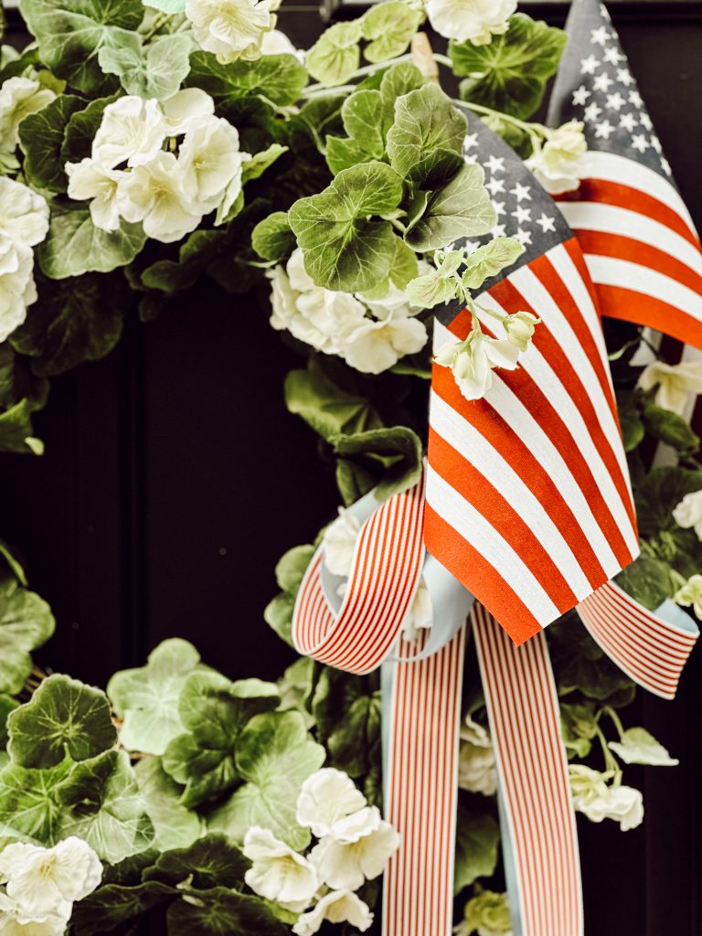 American flags tied to summer with red and white striped ribbon on front door.