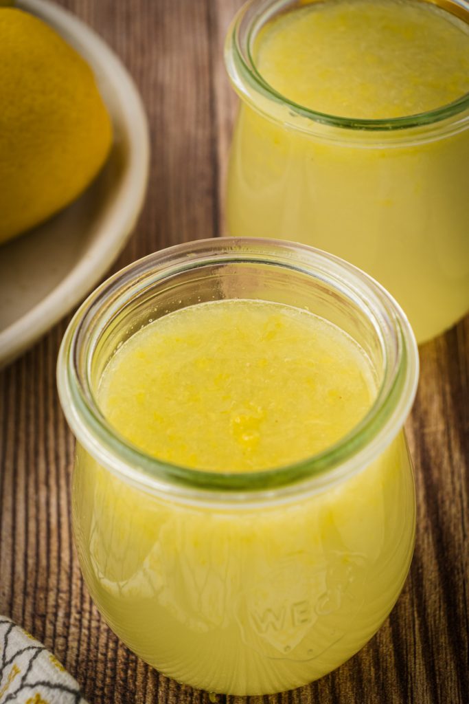 Mason jars with fresh homemade lemon concentrate on a wooden kitchen counter.