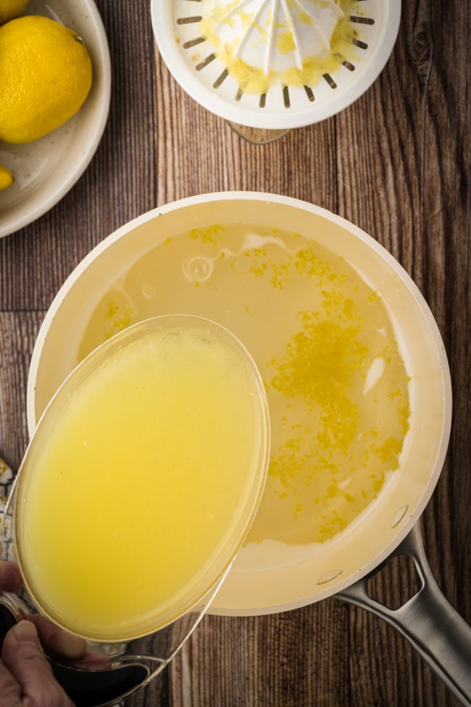 Pouring 2 cups of freshly squeezed lemon juice into the simple syrup to make fresh lemonade concentrate.