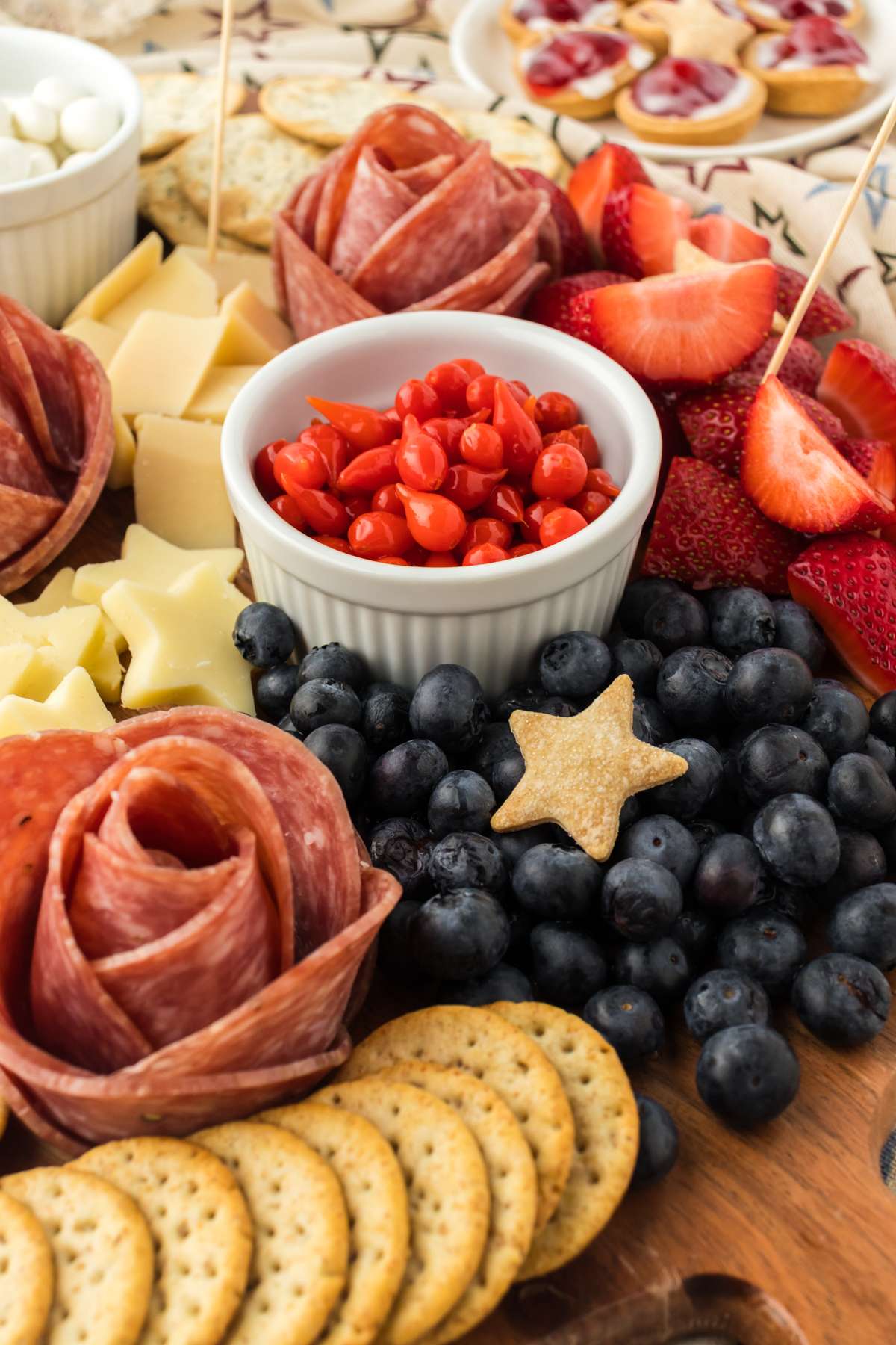 Fresh blueberries, salami, crackers, red peppers, strawberries, and cheese on a 4th of July charcuterie board.