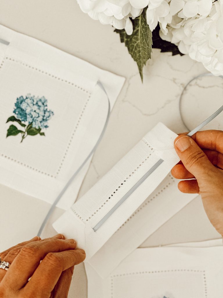 Blue satin ribbon threaded through the back of coaster for hanging on hutch. 