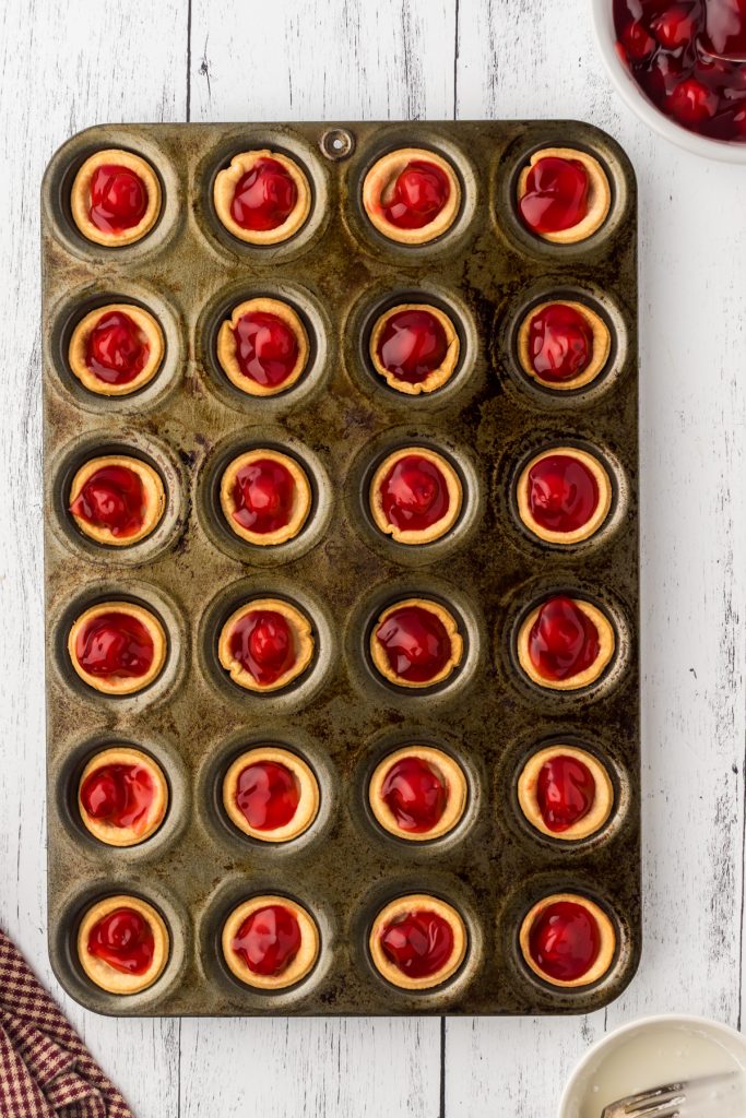 Canned cherry pie filling added to each of the pie crust cups in the mini muffin pan.