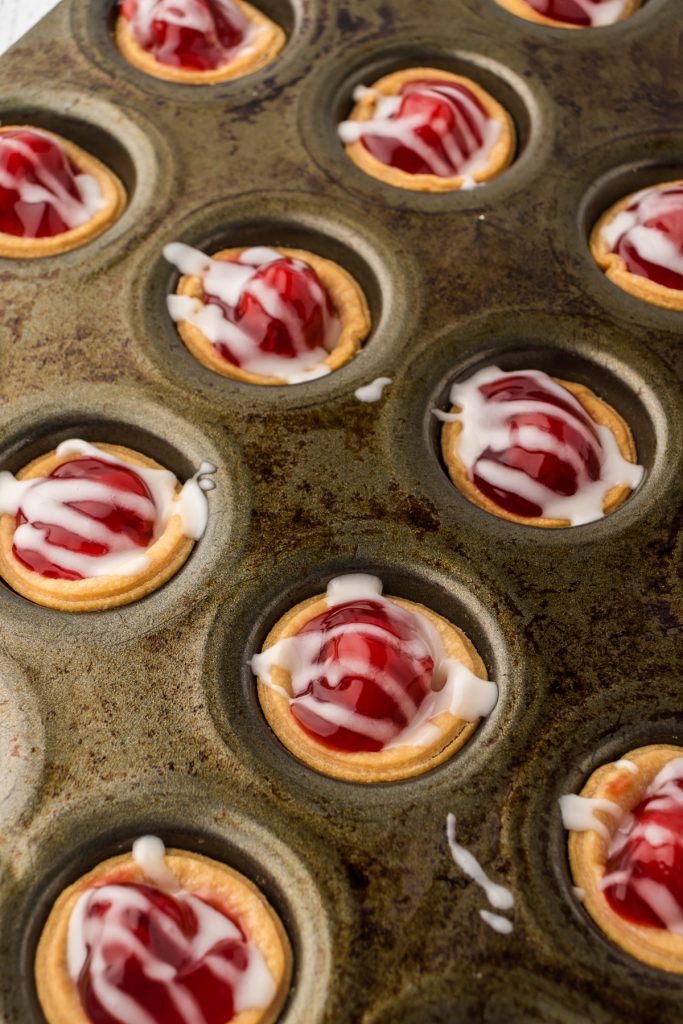 Mini cherry pies made with canned cherry filling in muffin tin ready for eating.