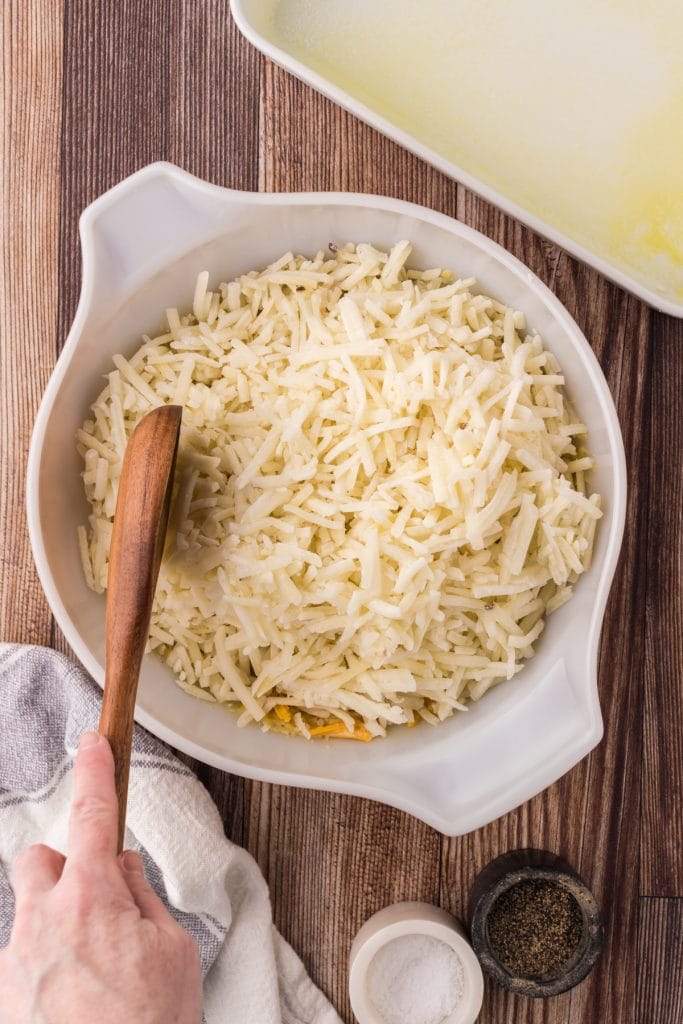 Once the cheesy sauce is combined, add in the frozen shredded hash brown potatoes.