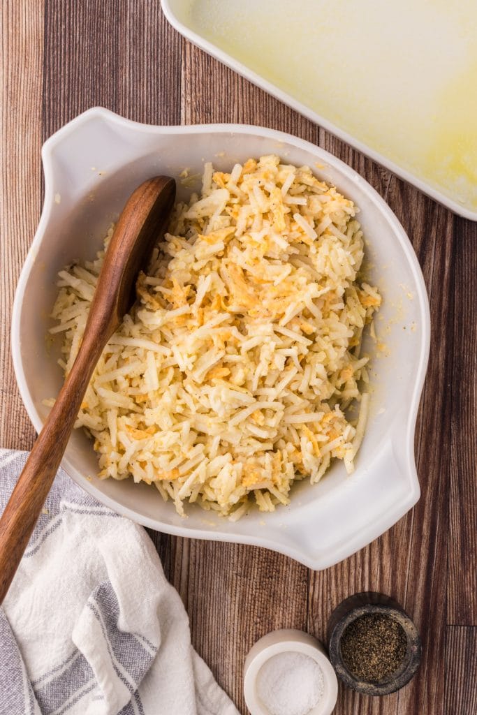 Frozen hash browns incorporated into the cheesy sauce in a large mixing bowl.