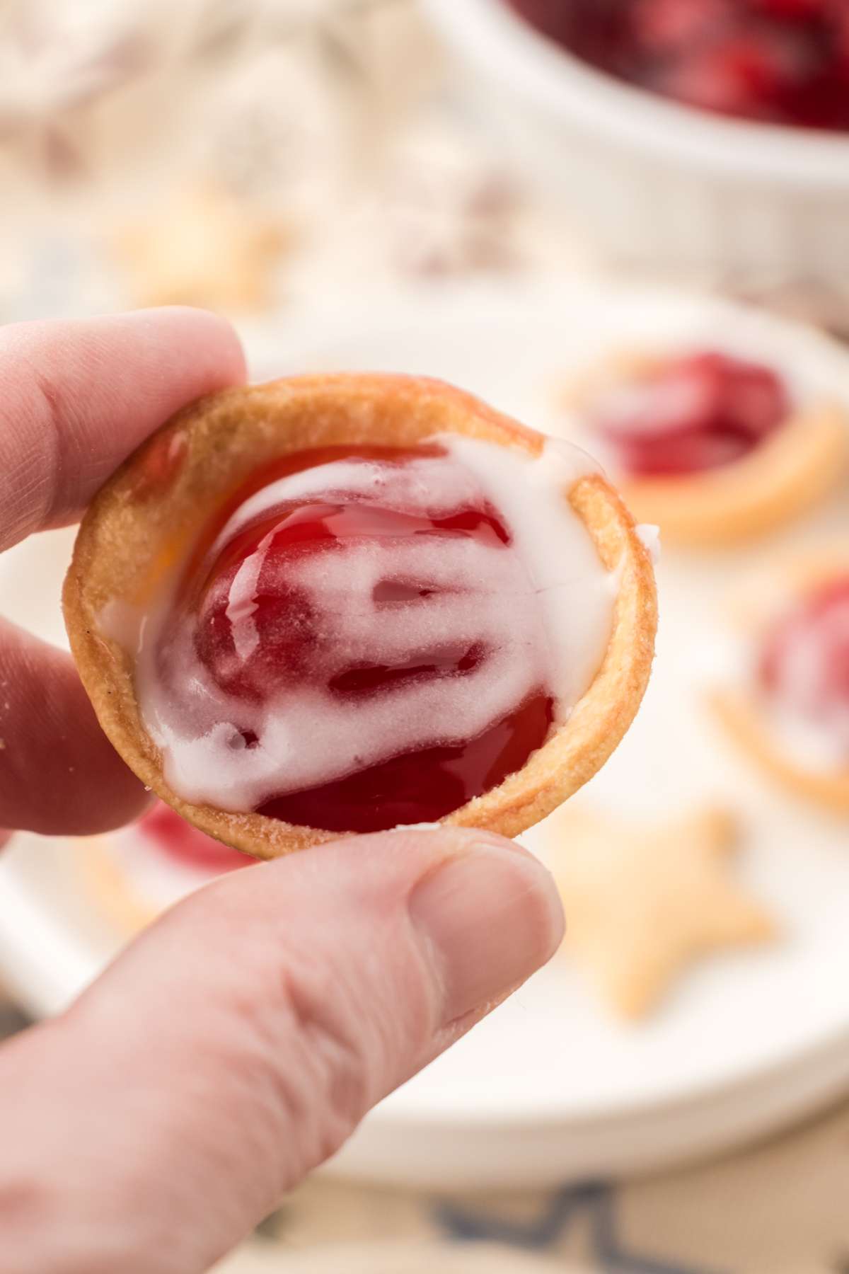 Heidi holding a mini cherry pie with a plate of more pies in the background.