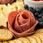 Salami Rosete on patriotic snack board along with crackers, cheese, fresh blueberries, and red peppers.